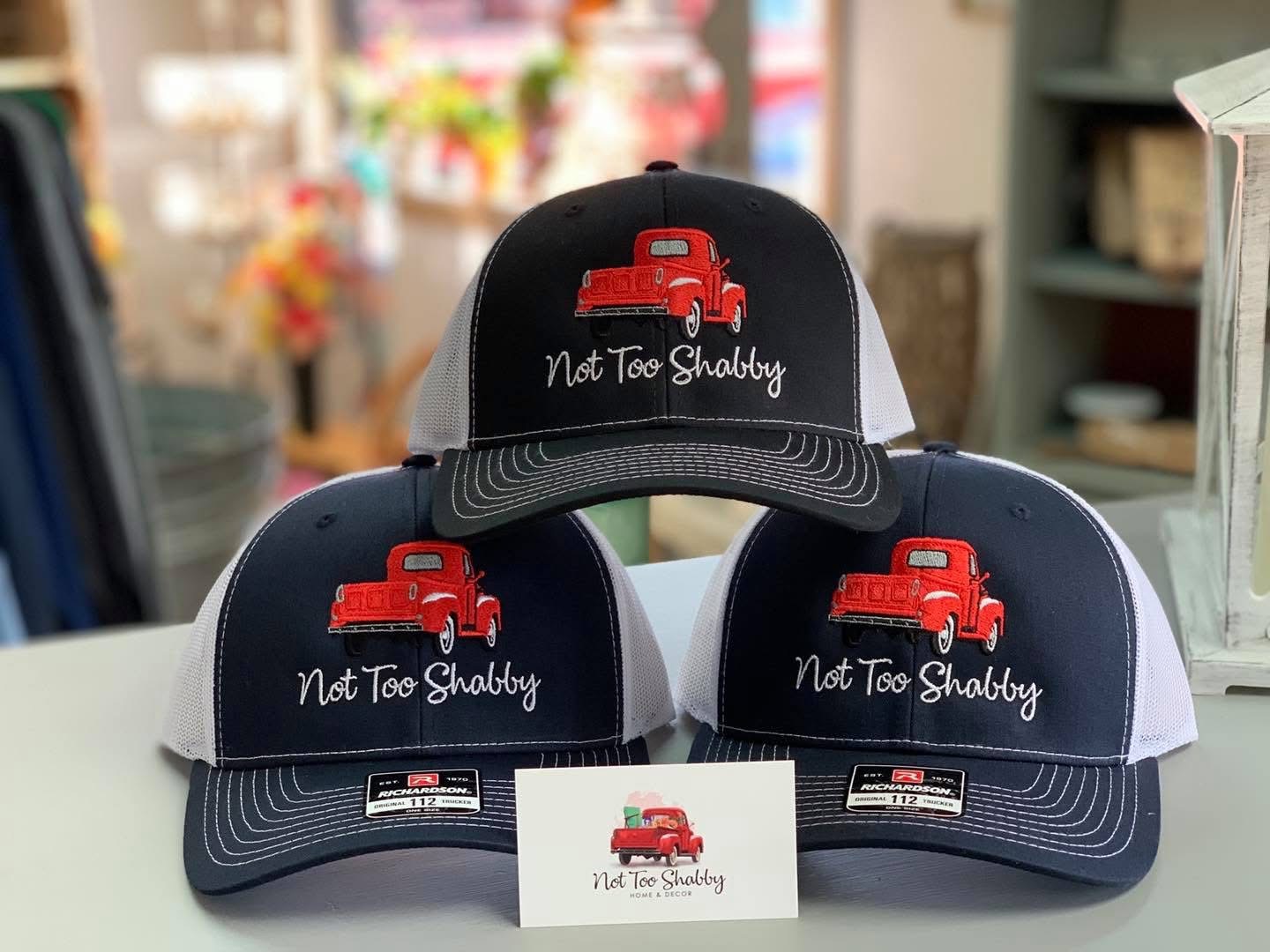 Navy and white trucker hats embroidered with the Not Too Shabby red truck logo